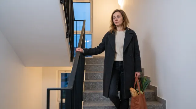 Mujer cansada con una bolsa de la compra parada en la escalera de su bloque - resistencia a la insulina, síntomas en mujeres